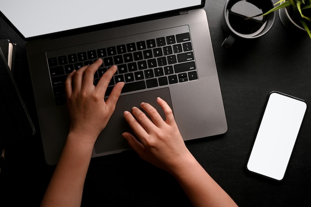 A female hands or businesswoman typing on notebook laptop keyboard on black workspace