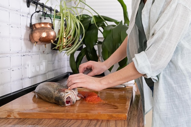 Female hands cutting fillet of red fish Red caviar Removing fish bones Butchering red fish meatxAxAFood concept