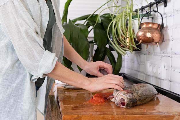 Female hands cutting fillet of red fish Red caviar Removing fish bones Butchering red fish meatxAxAFood concept