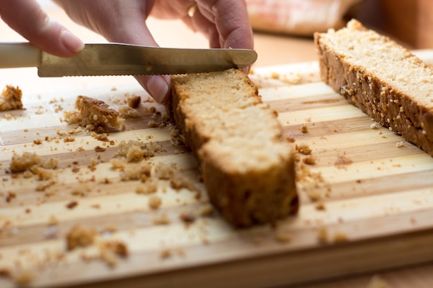 Female hands cutting and preparing cake crust on wooden  plate