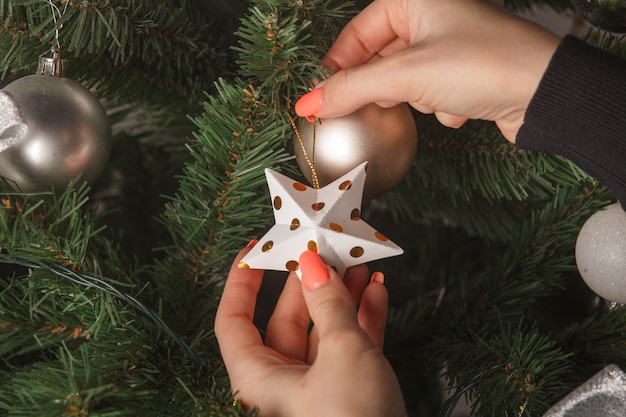 Female hands decorating christmas tree with toys