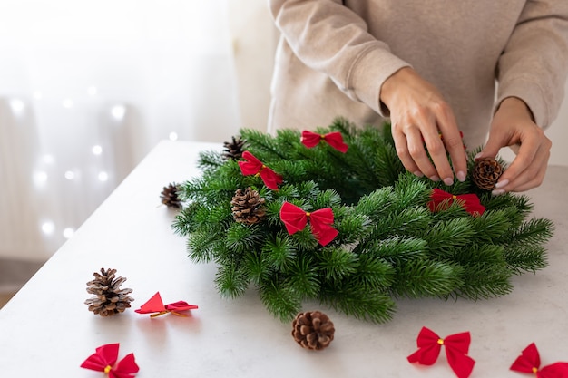 Female hands decorating Christmas wreath copy space