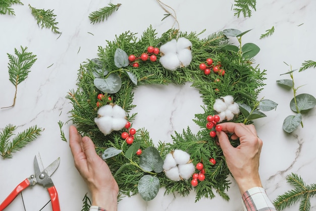 Female hands decorating DIY Christmas wreath