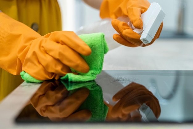 Female hands in gloves cleaning black kitchen surface Household concept