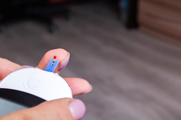 Female hands and glucometer measuring blood sugar