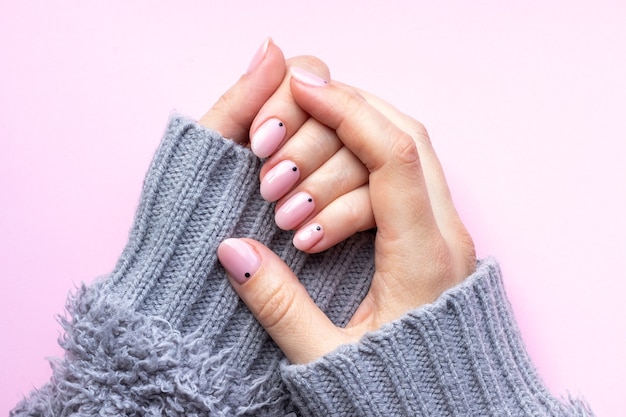 Female hands in a gray knitted sweater with trendy manicure