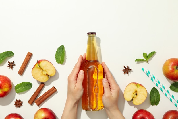 Female hands hold bottle of cider on white. Composition with cider