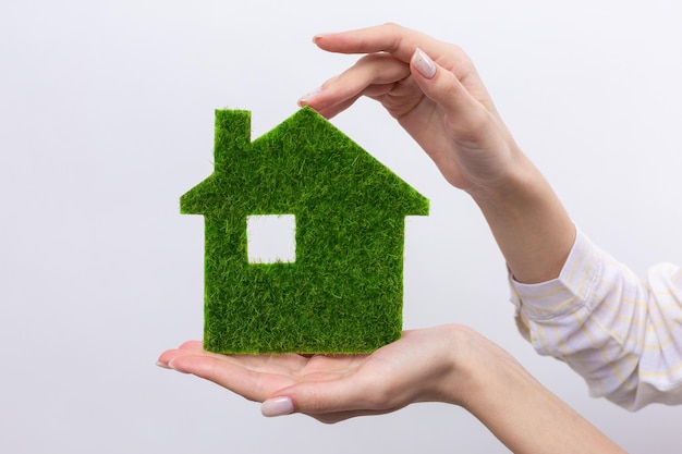 Female hands hold a model of a green house closeup Sale of ecological real estate of the future