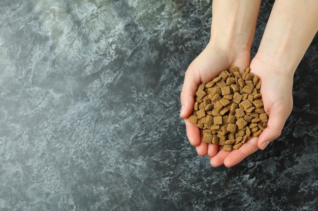 Female hands hold pet feed on black smokey