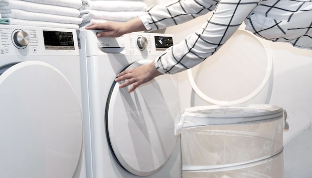 Female hands hold towels near wash and dry machines in the laundry