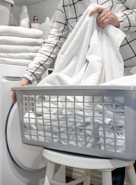 Female hands hold towels near wash and dry machines in the laundry