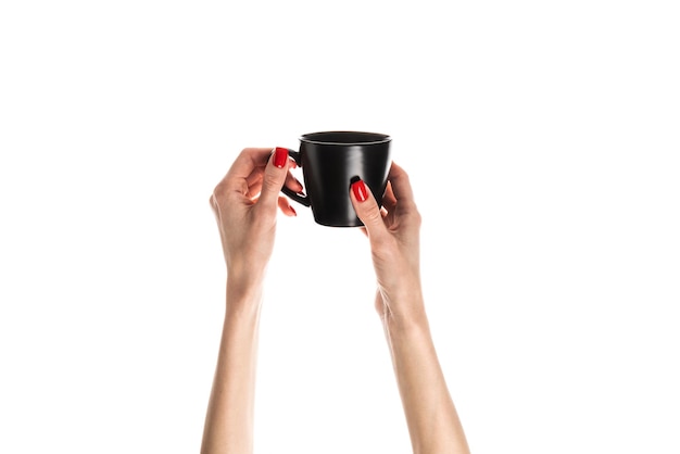 Female hands hold a white ceramic cup on white background Female hands with fresh red manicure Isolated on white background