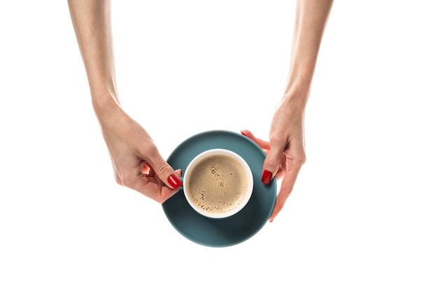 Female hands hold a white ceramic cup with a saucer on white background Coffee cup cup with coffee latte cappuccino threeinone coffee Female hands with fresh red manicure Isolated on white background