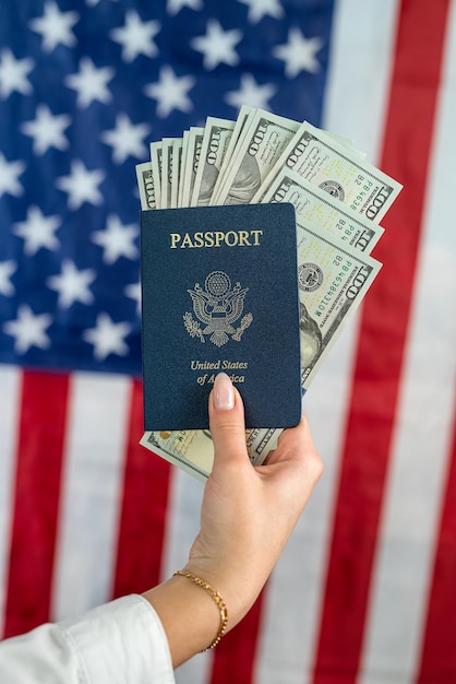 Female hands holding american passport with dollar cash over american flag closeup travel concept