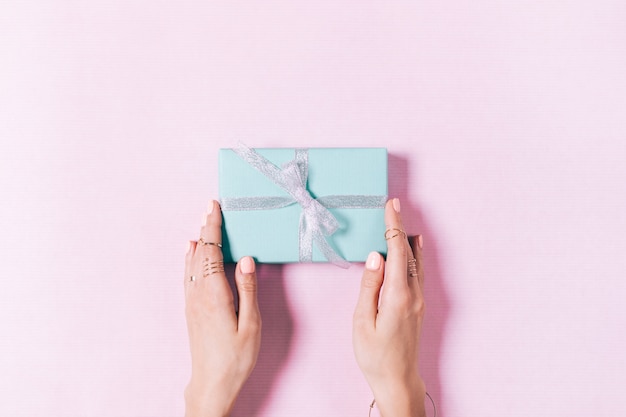 Female hands holding a blue box with a gift