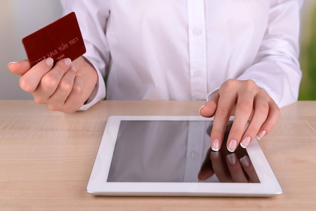 Female hands holding credit card and computer tablet on table on close up