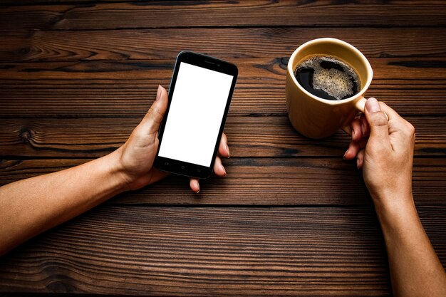 Female hands holding cup of coffee on wooden table