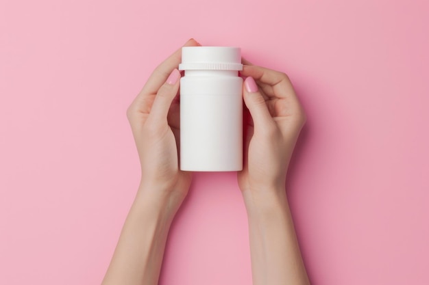 Female hands holding empty white squeeze bottle on pink background