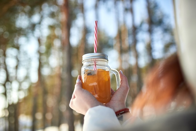 Female hands holding a glass of mulled wine on the   of a winter forest