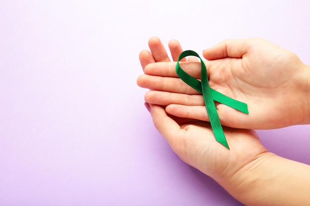 Female hands holding green organ transplant awareness ribbon