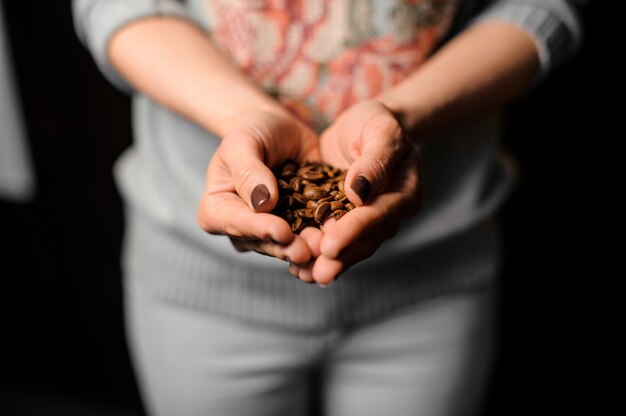 Female hands holding a handful of fresh coffee beans