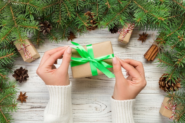 Female hands holding handmade present box in recycled paper on white wooden table background. christmas preparation , Gift wrapping background