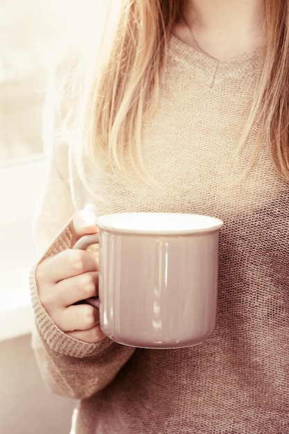 Female hands holding hot cup of coffee or tea in morning sunlight Morming drinks and good mood