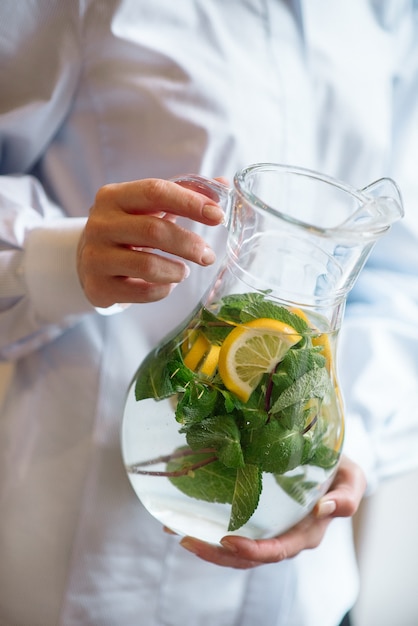 Photo female hands holding a jug of lemonade