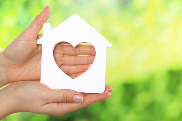 Female hands holding model of house on bright background