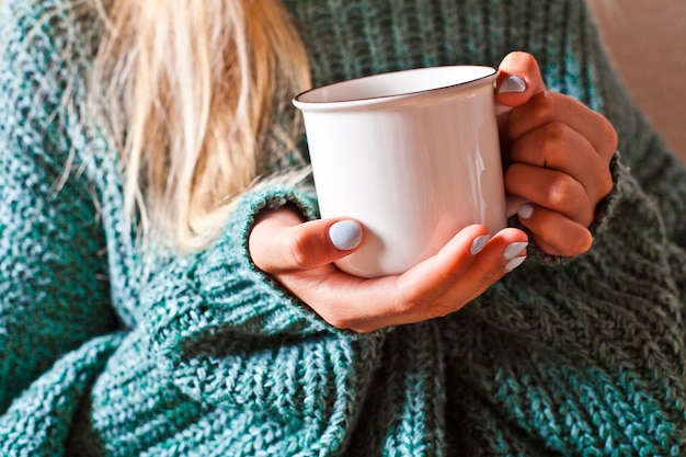 Female hands holding mug of hot tea with lemon