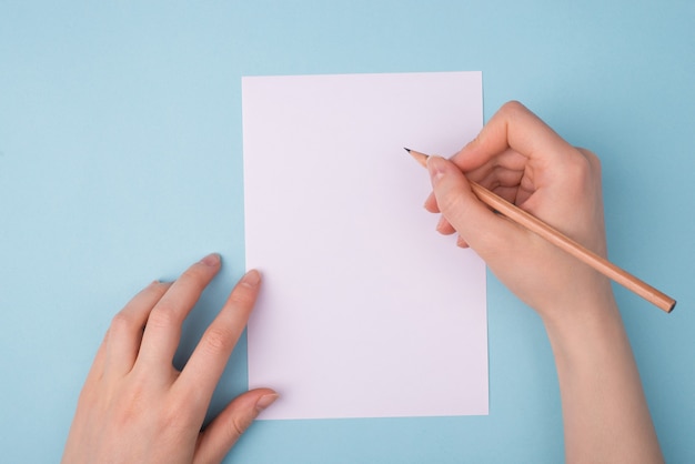 Female hands holding pencil over white sheet of paper