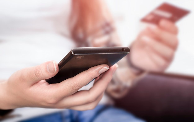 Female hands holding a phone and a credit card. front view, selective focus