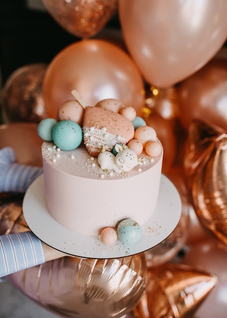 Female hands holding a pink cake on a wooden plate for a birthday party decorated with chocolate toys