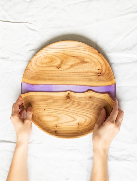 Female hands holding round wooden craft tray with a lilac resin insert