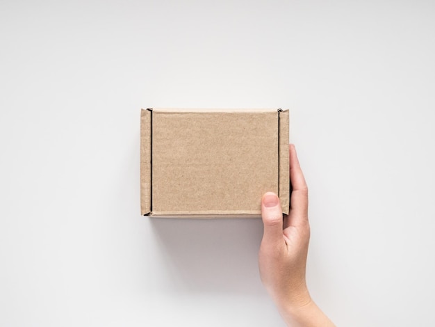 female hands holding a small cardboard box on a white background. packaging and delivery concept