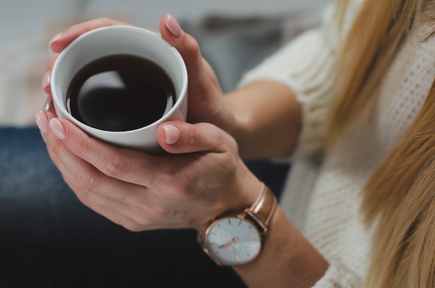 Female hands holding a white mug with beverage. Life style concept. Top view. Close up