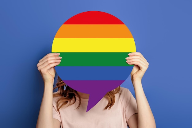 Female hands holds speech bubble with LGBT flag community isolated on blue background Close up