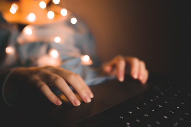 Female hands on laptop, the girl's hand works at night on gadget.