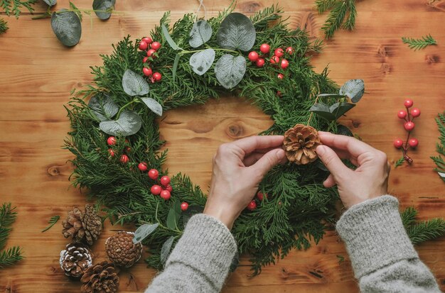 Female hands making Christmas wreath DIY winter home decoration