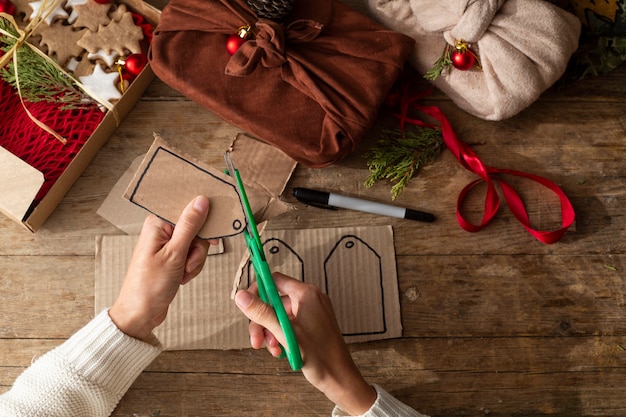 Female hands making gift tags from craft cardboard