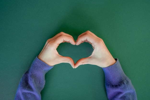 Photo female hands making sign heart by fingers