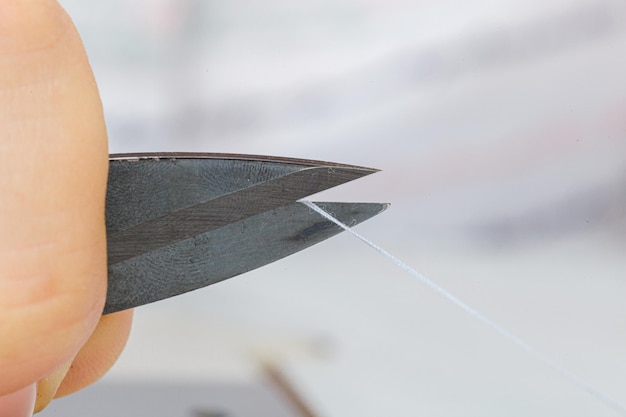 Female hands of a master tailor cuts a thread with scissors