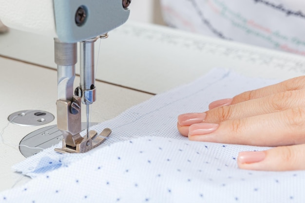 Female hands of a master tailor at work a sewing machine needle