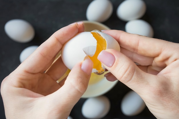 female hands open the shell of chicken egg