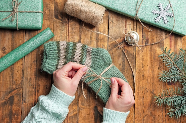 Female hands preparing gifts for Christmas on wooden table