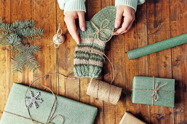 Female hands preparing gifts for Christmas on wooden table