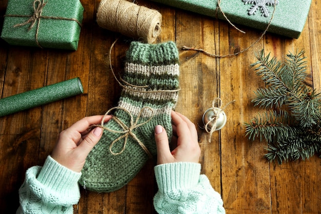 Female hands preparing gifts for Christmas on wooden table