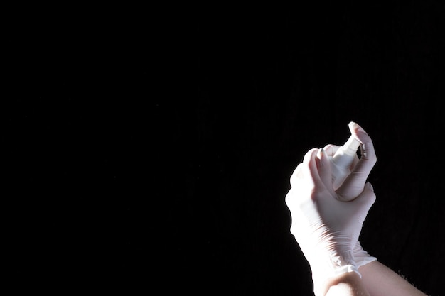 Female hands in protective gloves hold a plastic spray bottle with a chemical