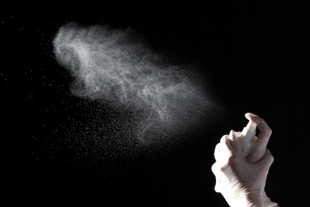 Female hands in protective gloves hold a plastic spray bottle with a chemical