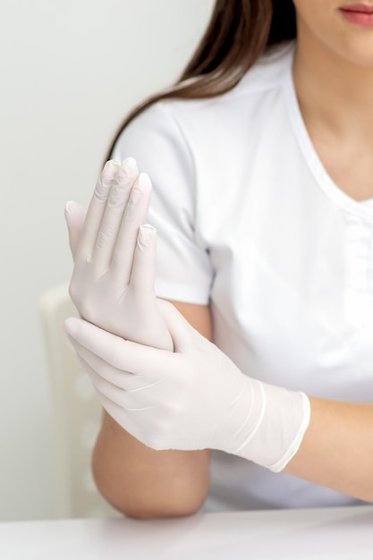 Photo female hands putting on protective white latex medical gloves during epidemic in quarantine